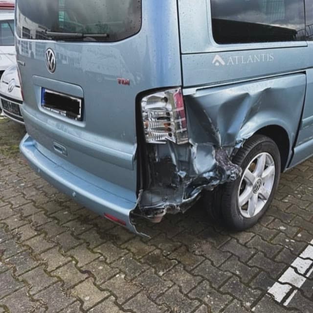 Unfallschaden am Heck eines hellblauen VW-Busses, Seitenwand und Rückleuchte eingedrückt